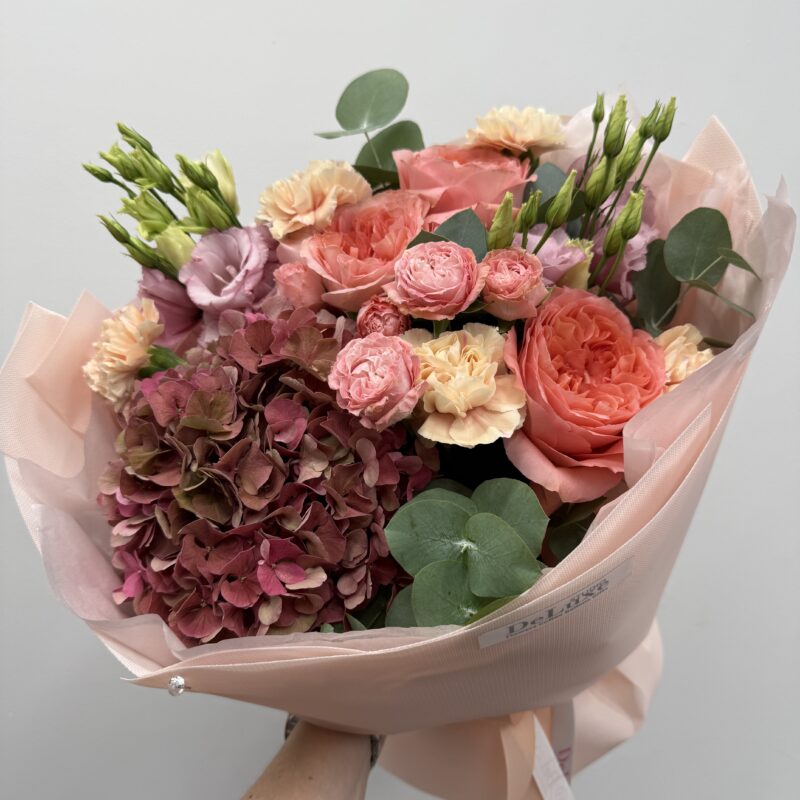 Bukiet z hortensji, róż, eustom i goździków Deluxe w pastelowych odcieniach różu i kremu, z dodatkiem eukaliptusa. Ręcznie układany przez florystów Studio Deluxe w Poznaniu.